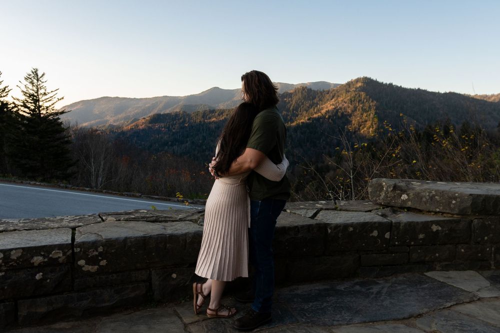 Mountain landscape engagement photos with couple on scenic overlook at sunset.