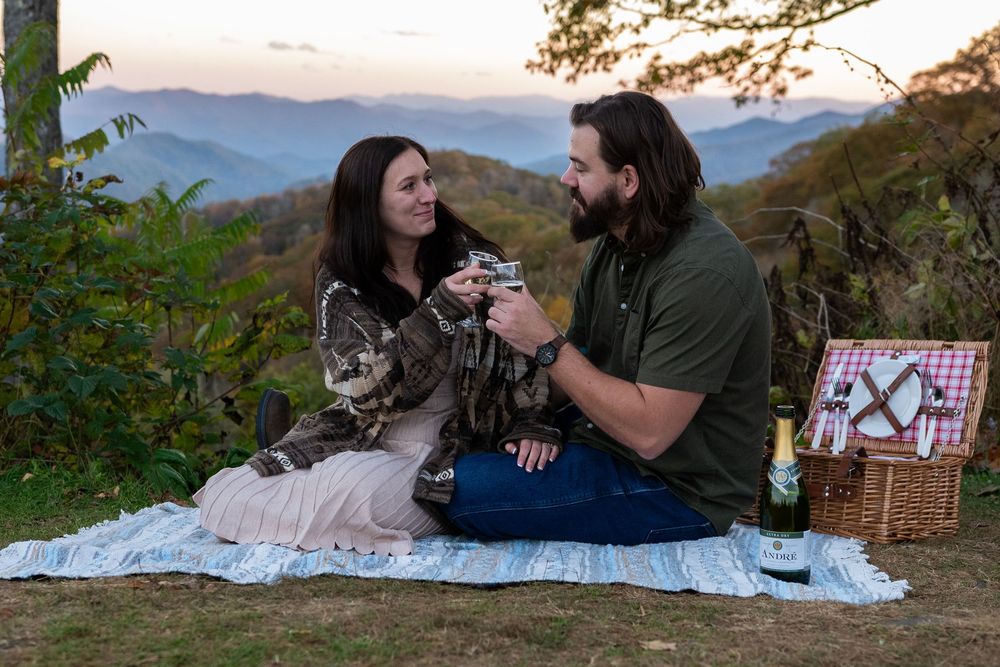 Scenic mountain overlook picnic with blanket and basket during sunset.