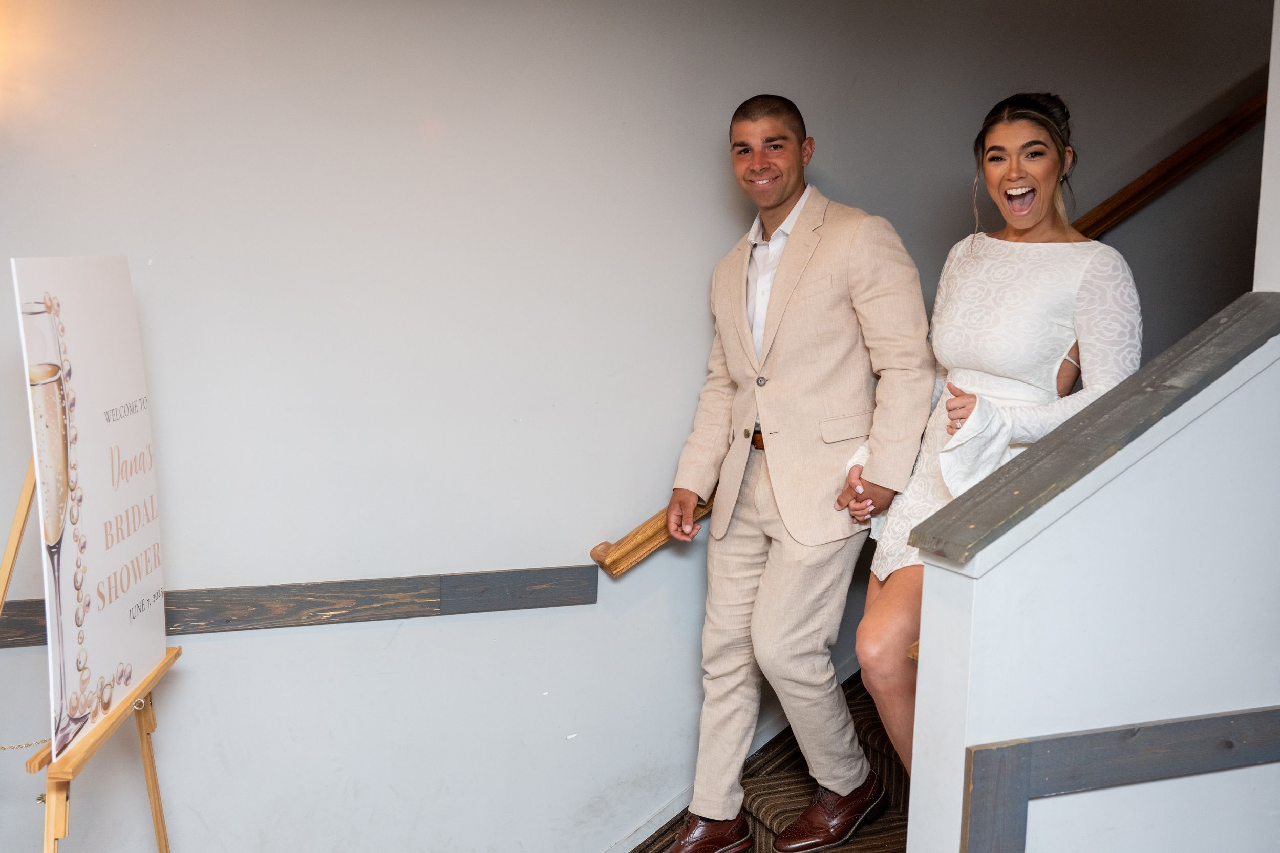 Couple descends elegant staircase in formal attire during wedding celebration.