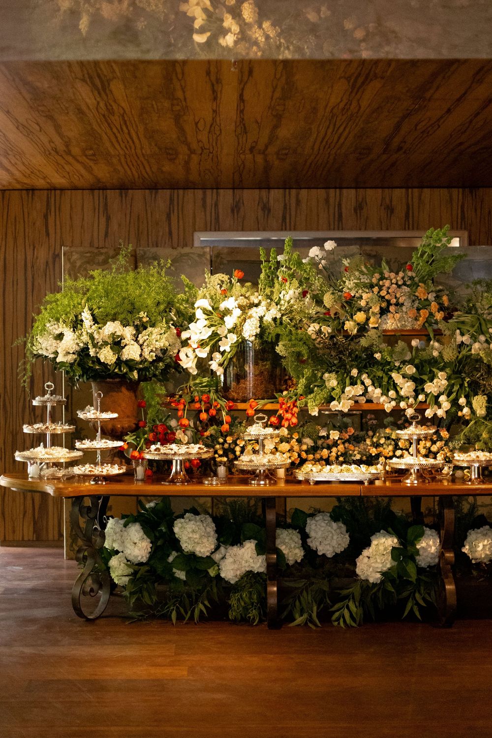 Elegant floral arrangements with white hydrangeas and greenery decorate a rustic wooden table at an upscale event venue.