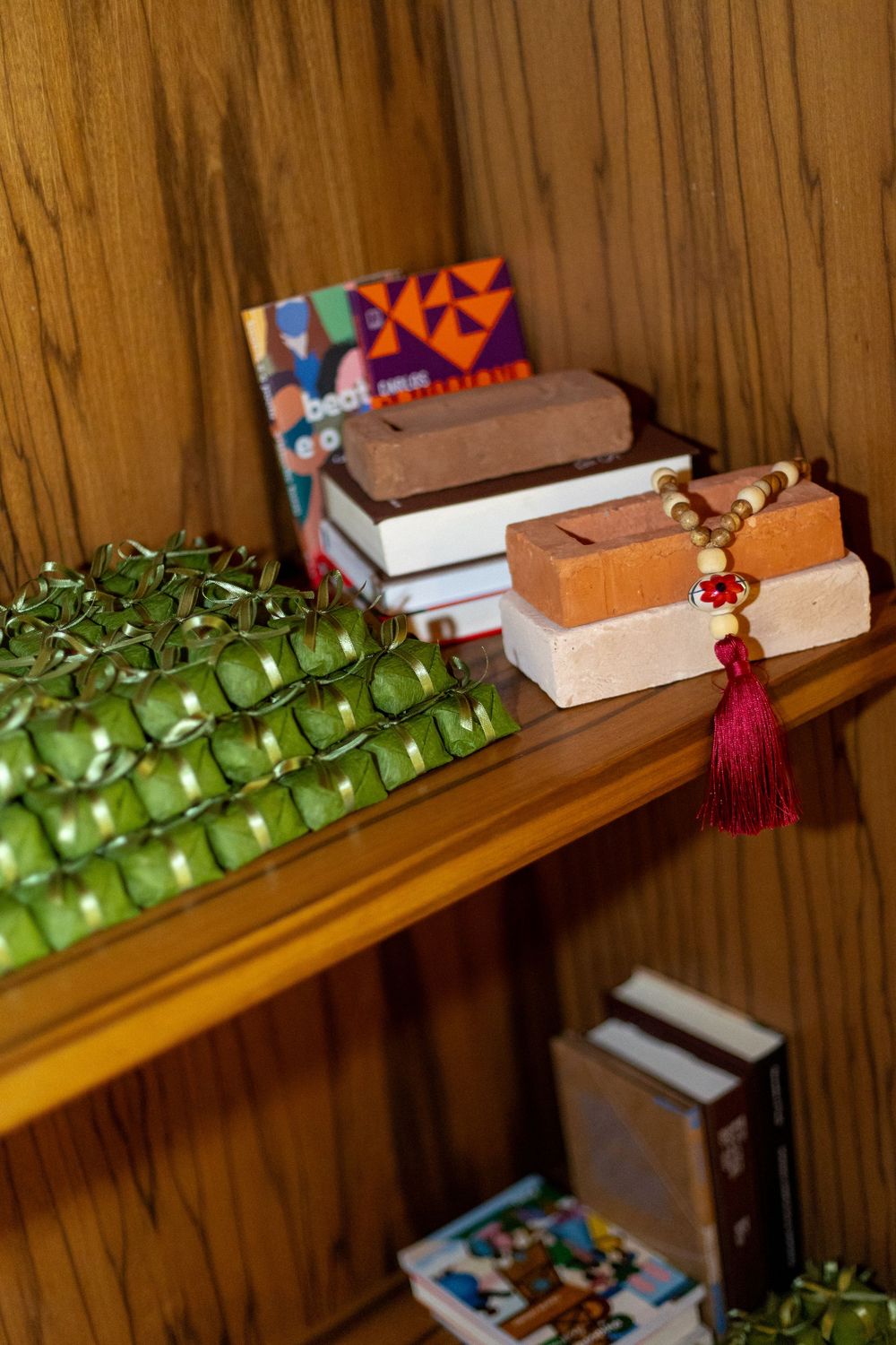 Green apples and books arranged on a wooden shelf with decorative tassels.