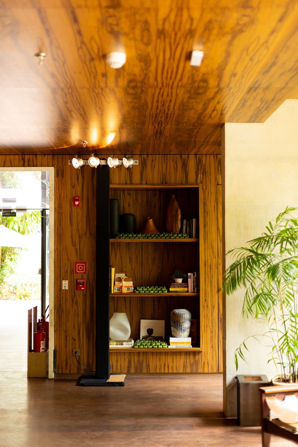Modern wood-paneled event space interior with plants and warm lighting.