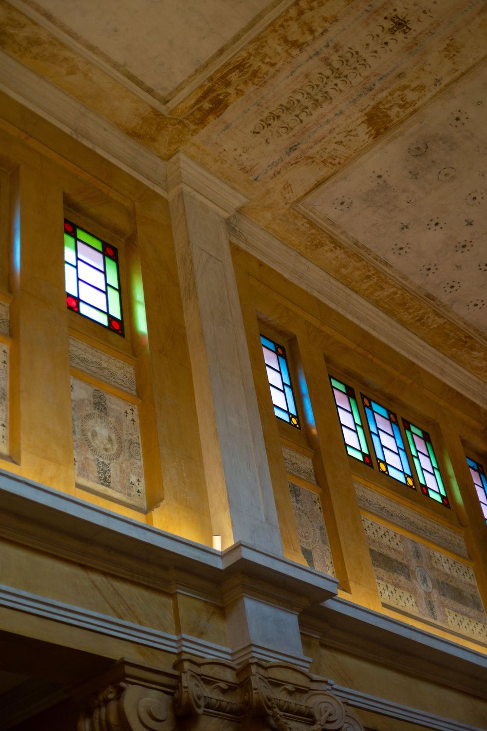 Ornate cathedral ceiling with stained glass windows and decorative moldings illuminated in warm light.