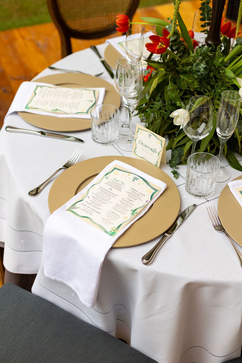 Formal dining table setup with white tablecloths, place settings, and red and white floral centerpieces.