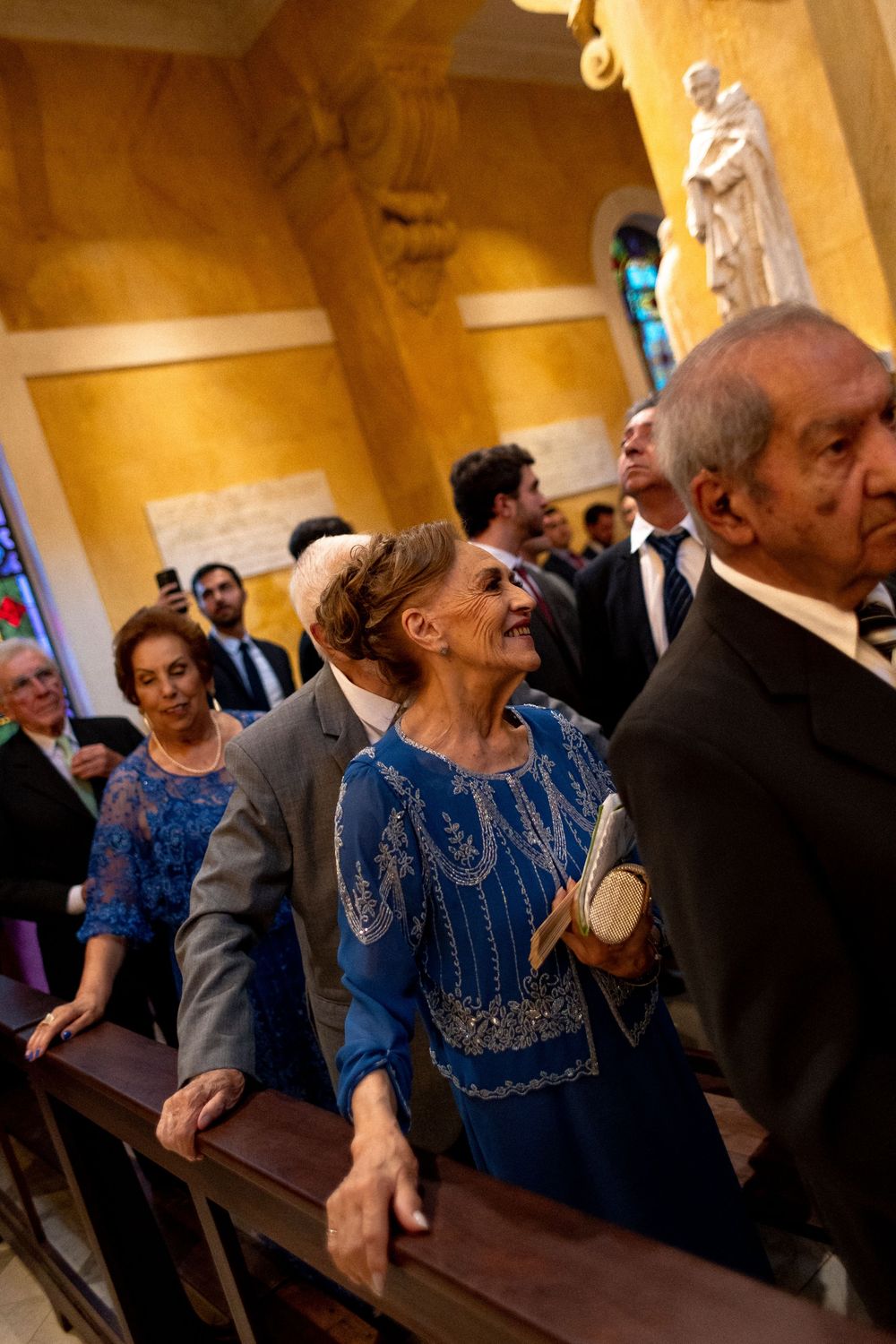 Wedding guests seated in church pews share joyful moments during the ceremony.