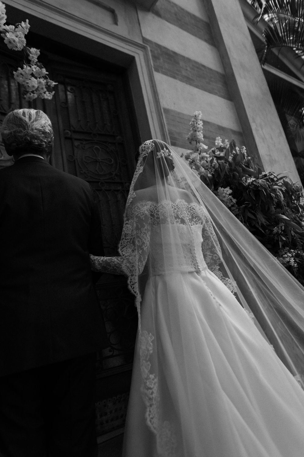 An elegant lace wedding gown with long train displayed in dramatic black and white photography.