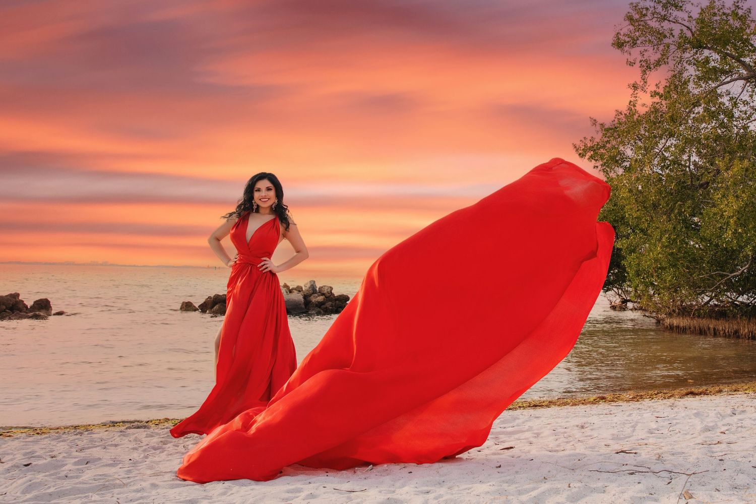 A flowing red dress billows dramatically against a pink sunset sky on a sandy beach. Flying Dress Photos