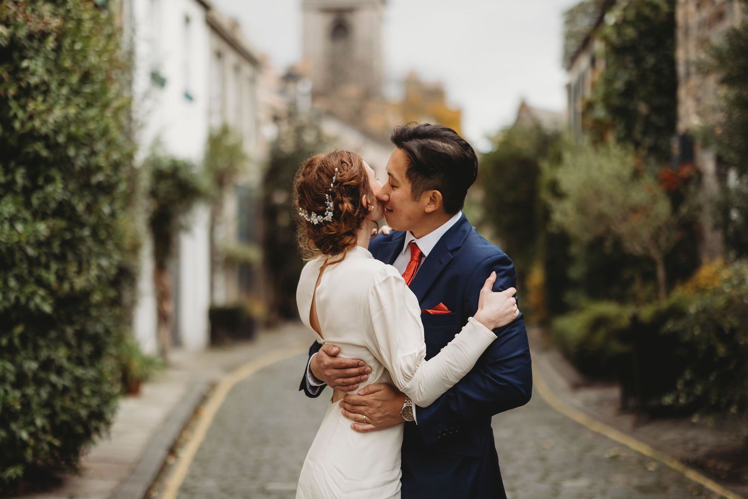 Romantic couple embraces in a garden setting during an outdoor photoshoot.
