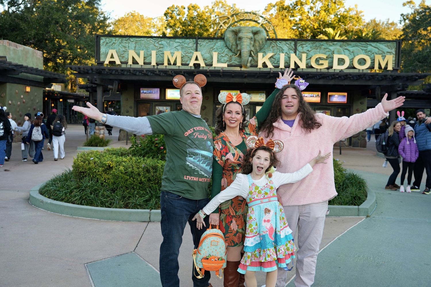A series of people enjoying their visit to Disney's Animal Kingdom theme park entrance during daytime.