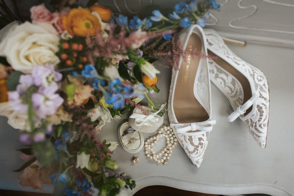 Wedding accessories including bridal shoes and floral arrangements in pastel colors.