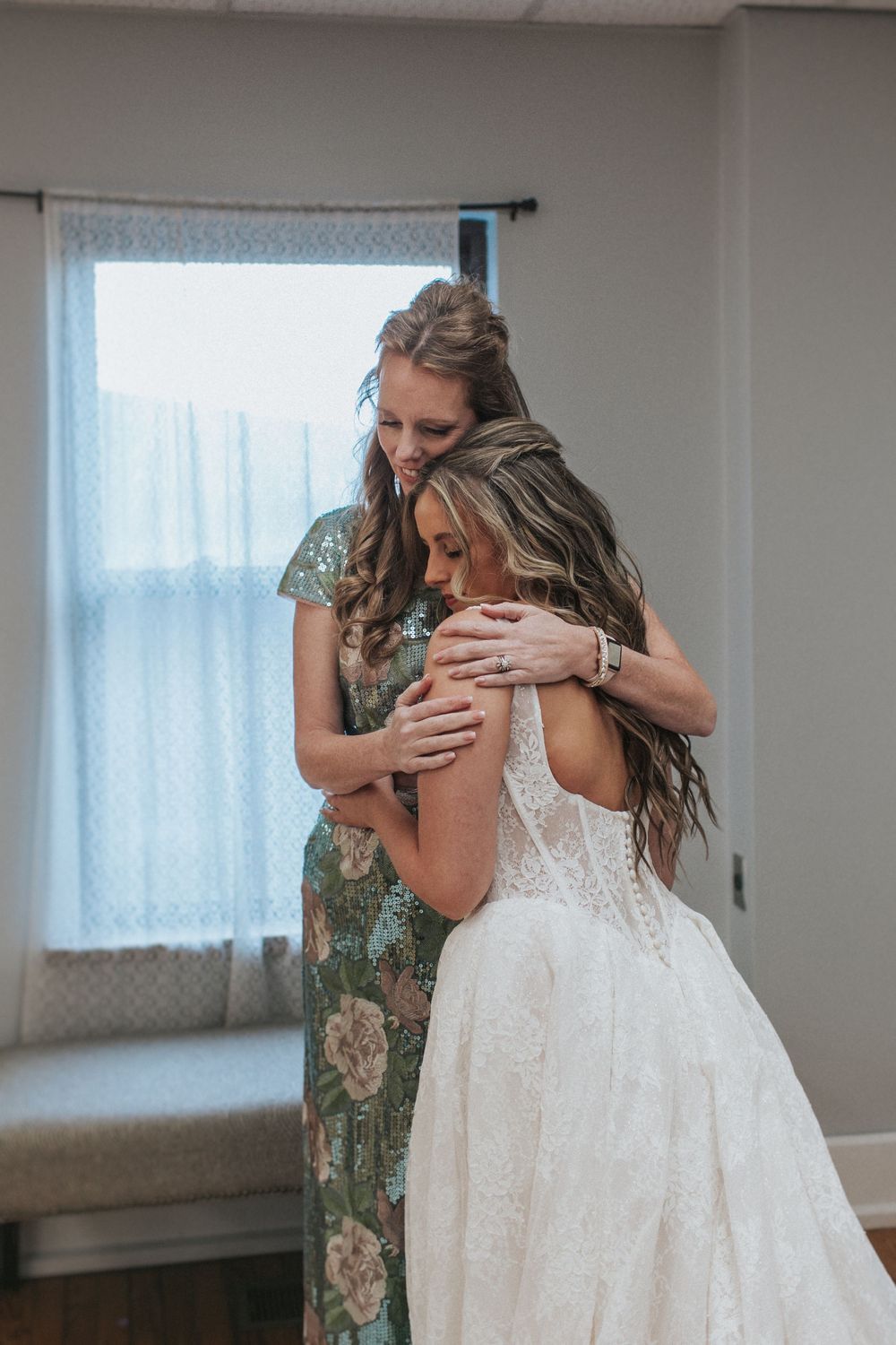 Emotional moment during wedding preparations in a bright room.