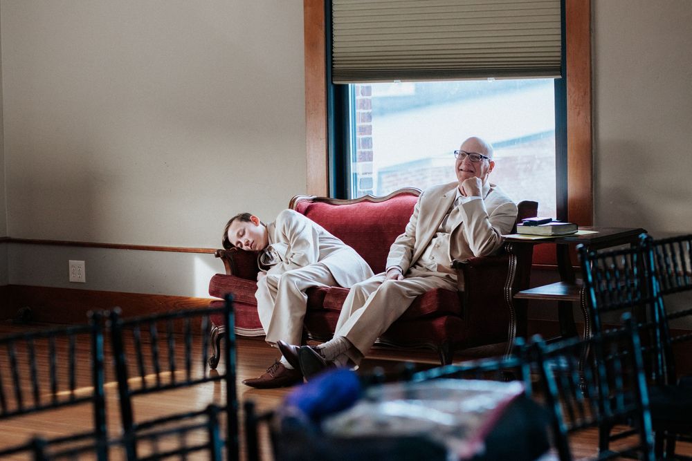 Two people relax casually on chairs in a sunlit room.