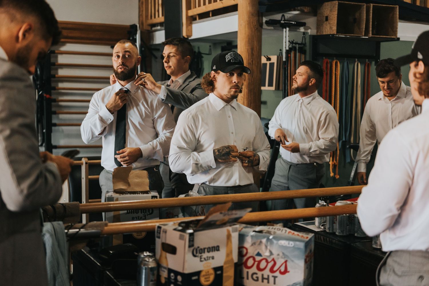 A group of people in white shirts gather in a rustic wooden room for a casual social event.