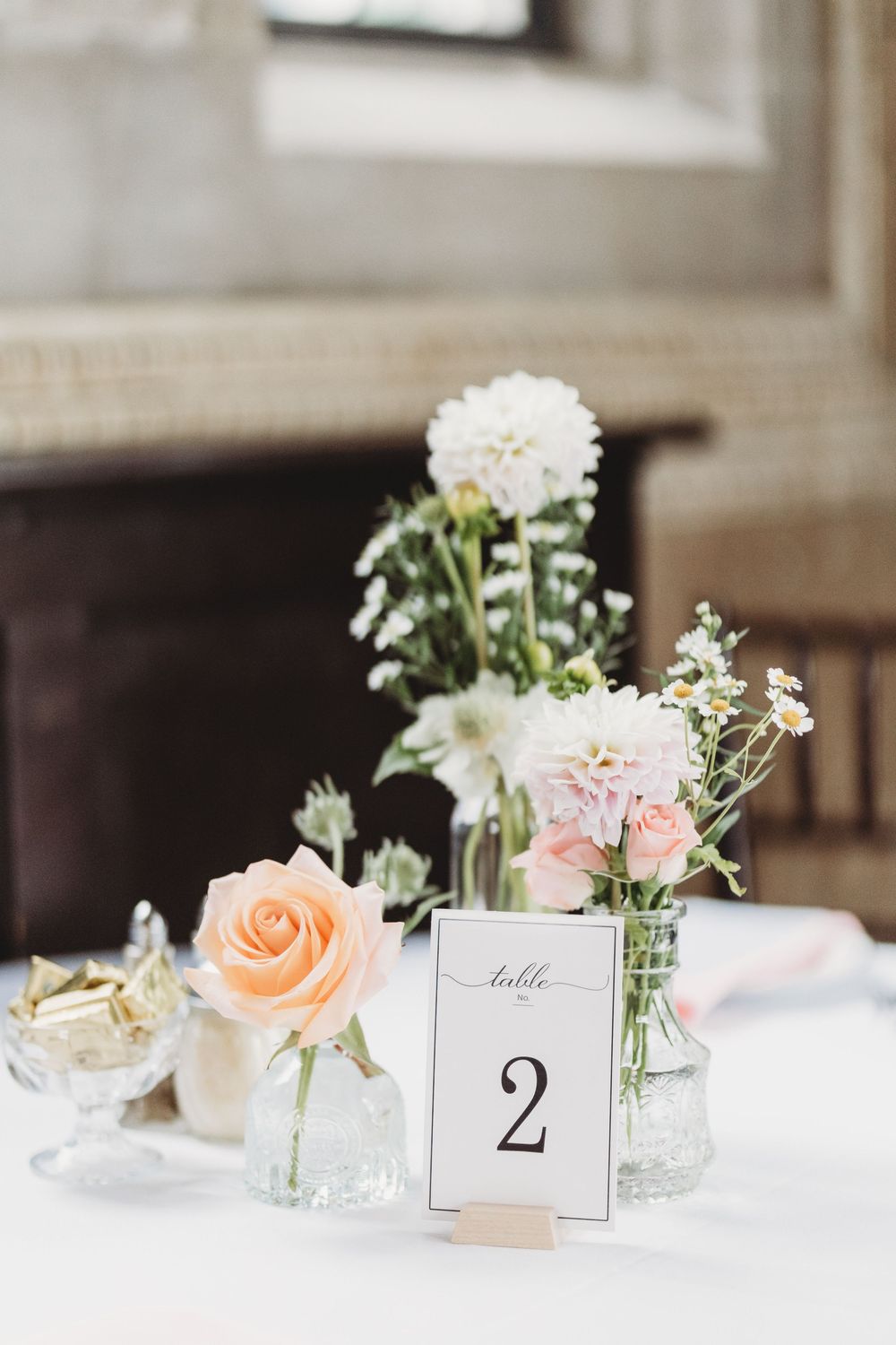 Elegant wedding reception table settings with delicate floral centerpieces and table number cards.