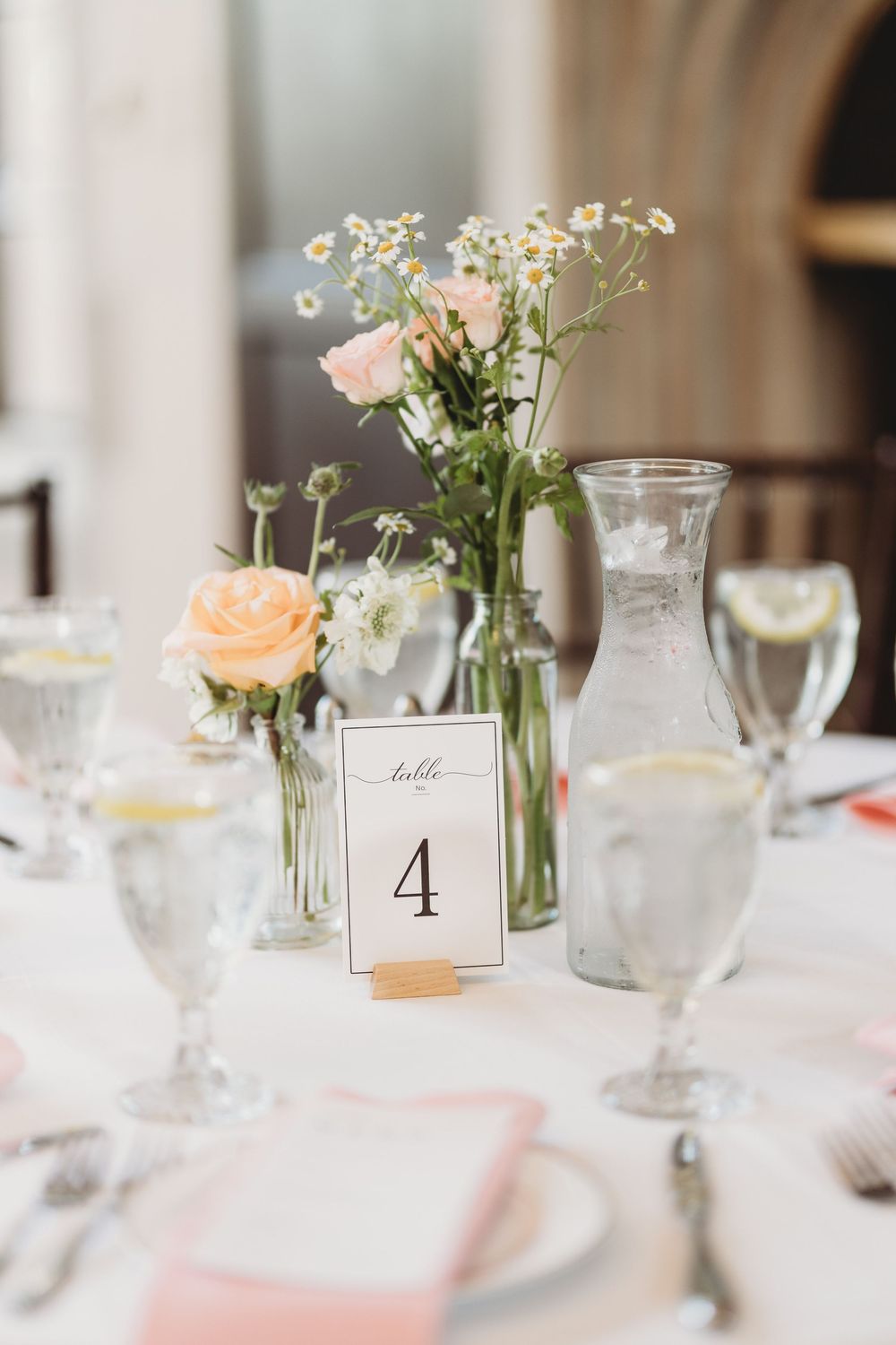 Elegant wedding reception table setting with floral centerpieces and table numbers.
