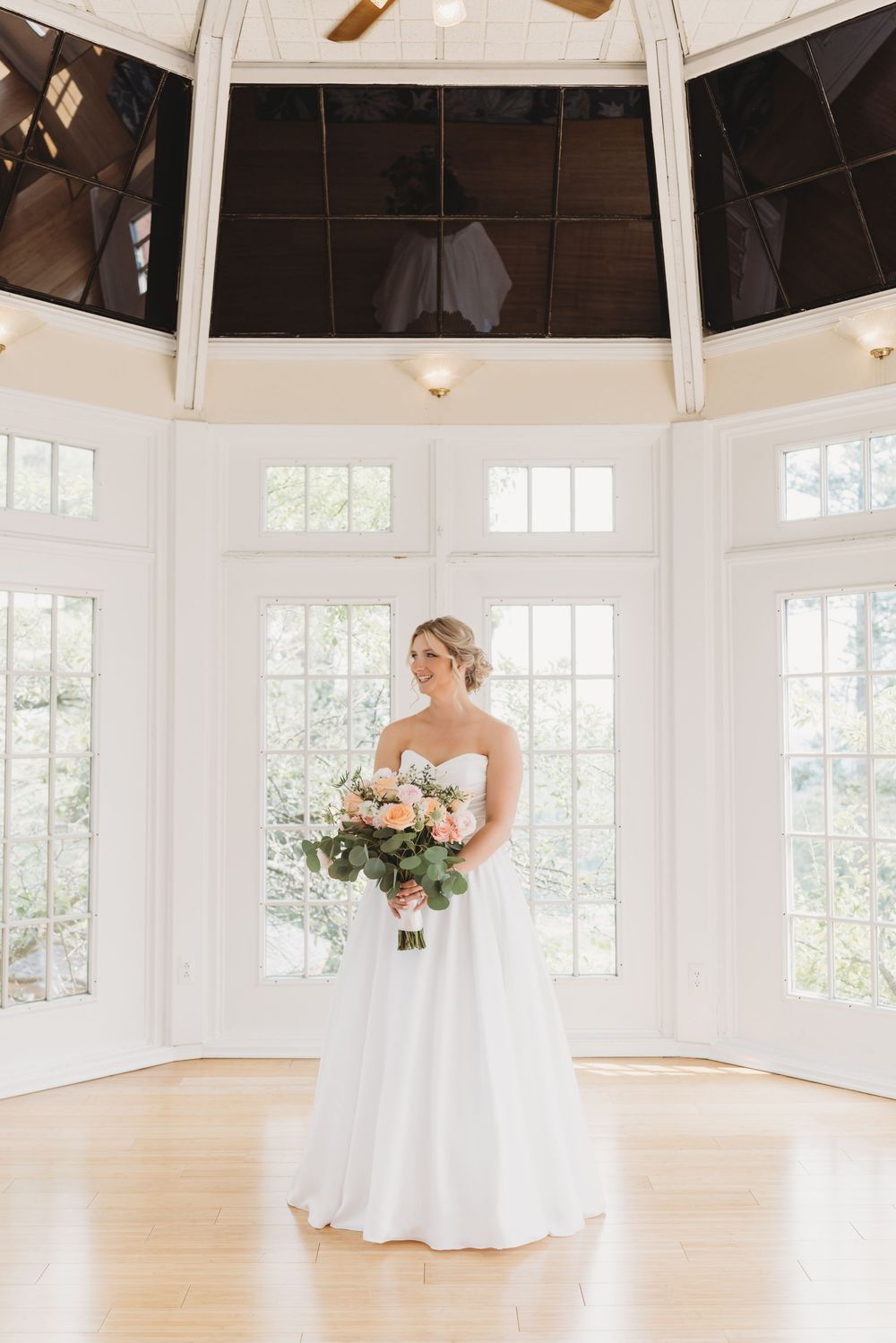 A bright white octagonal room with hardwood floors and large windows serves as an elegant wedding venue.