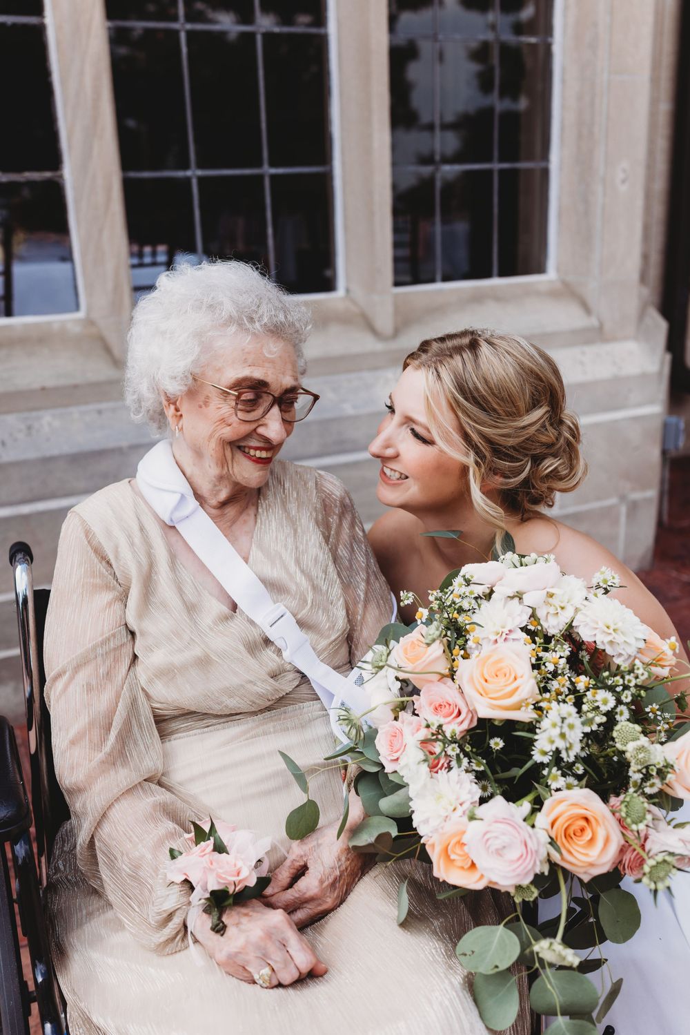 Tender moment shared over beautiful peach and white floral bouquet with eucalyptus leaves.