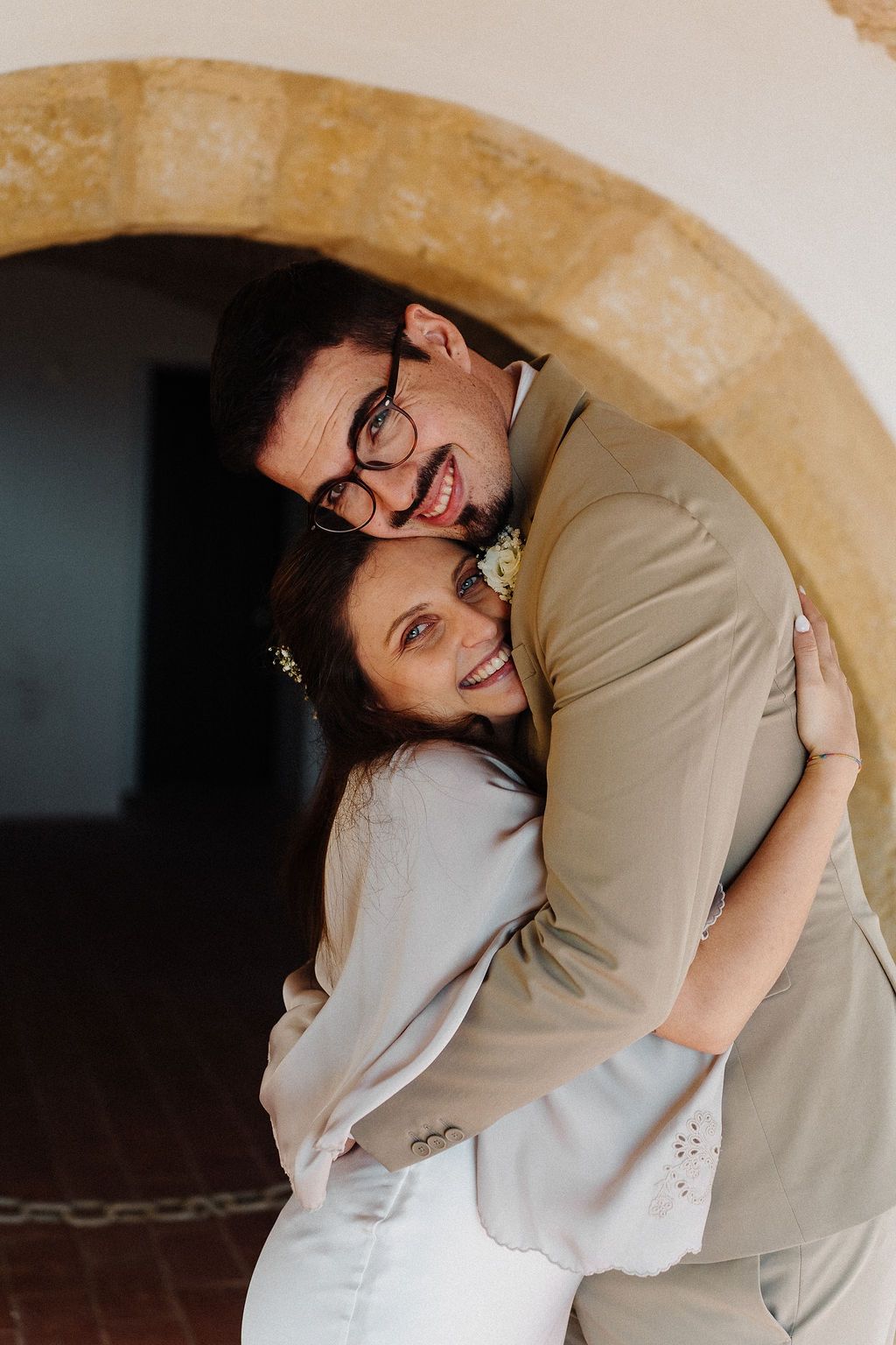 Romantic moment captured under an arched architectural feature.
