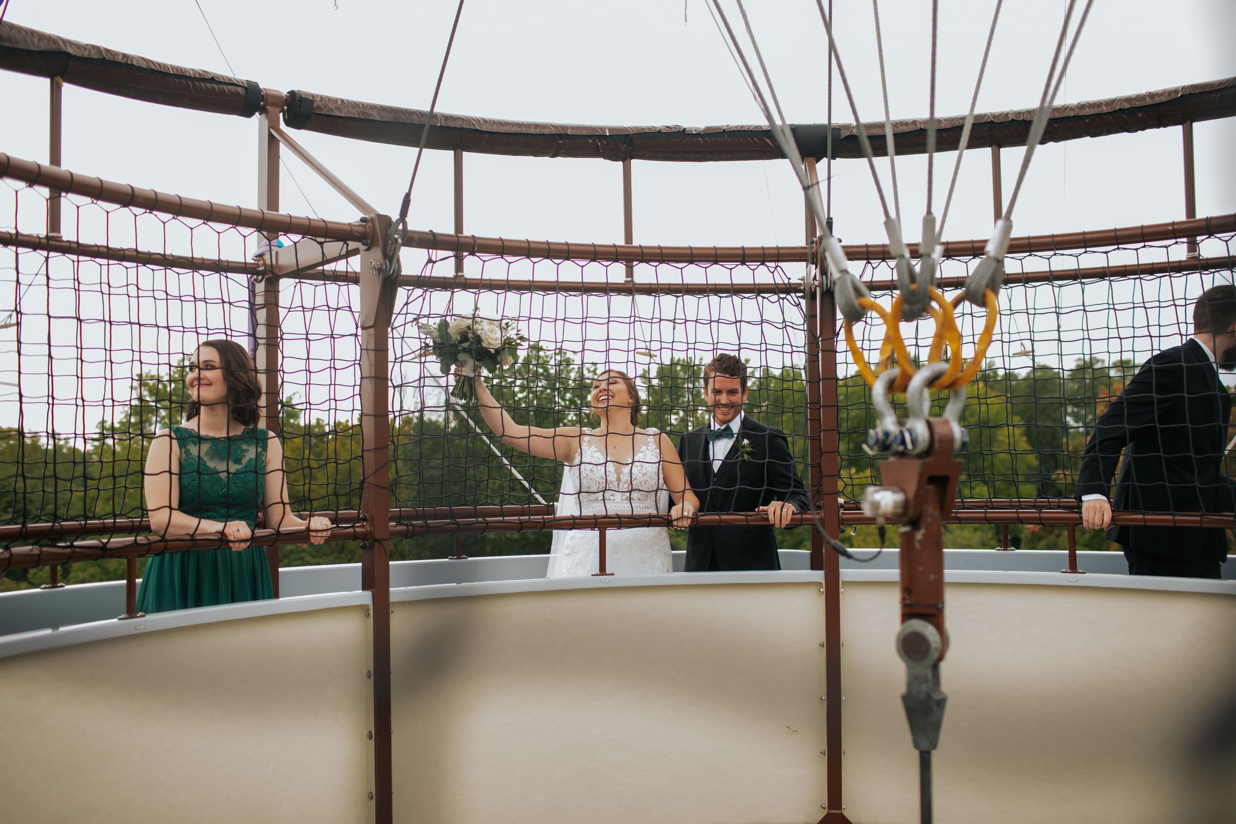 Wedding party gathered in a unique circular structure with netting and ropes.