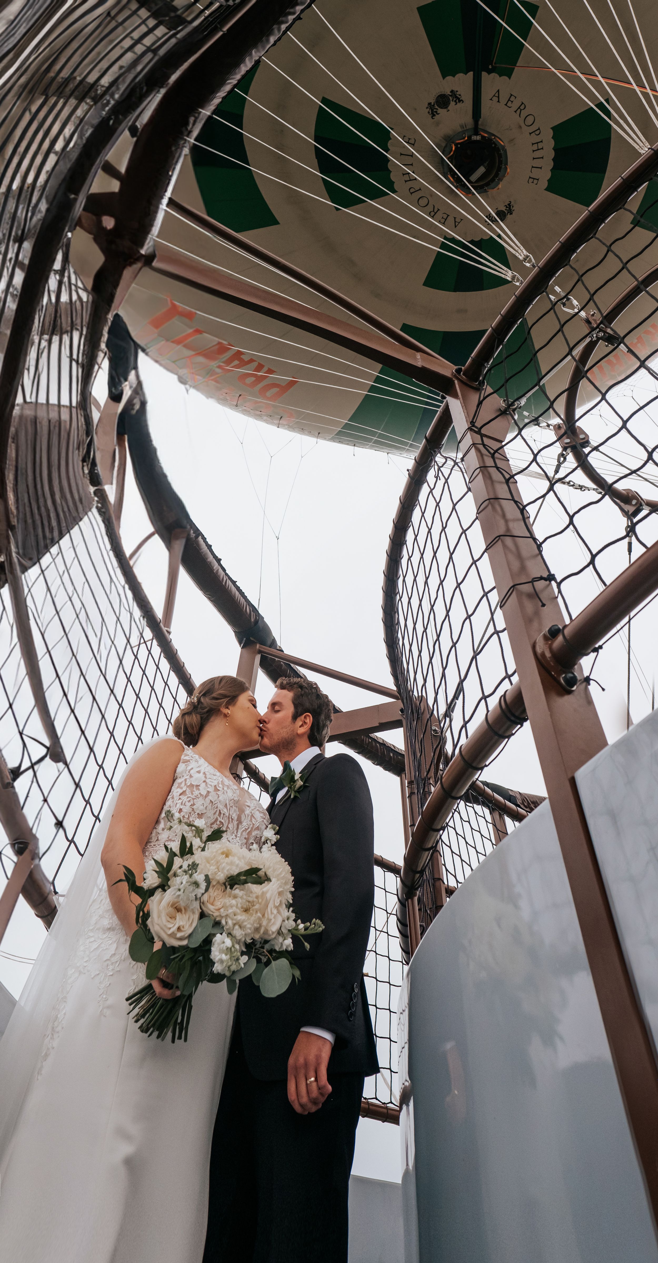 An intimate wedding moment captured inside a circular mesh enclosure with white flowers.