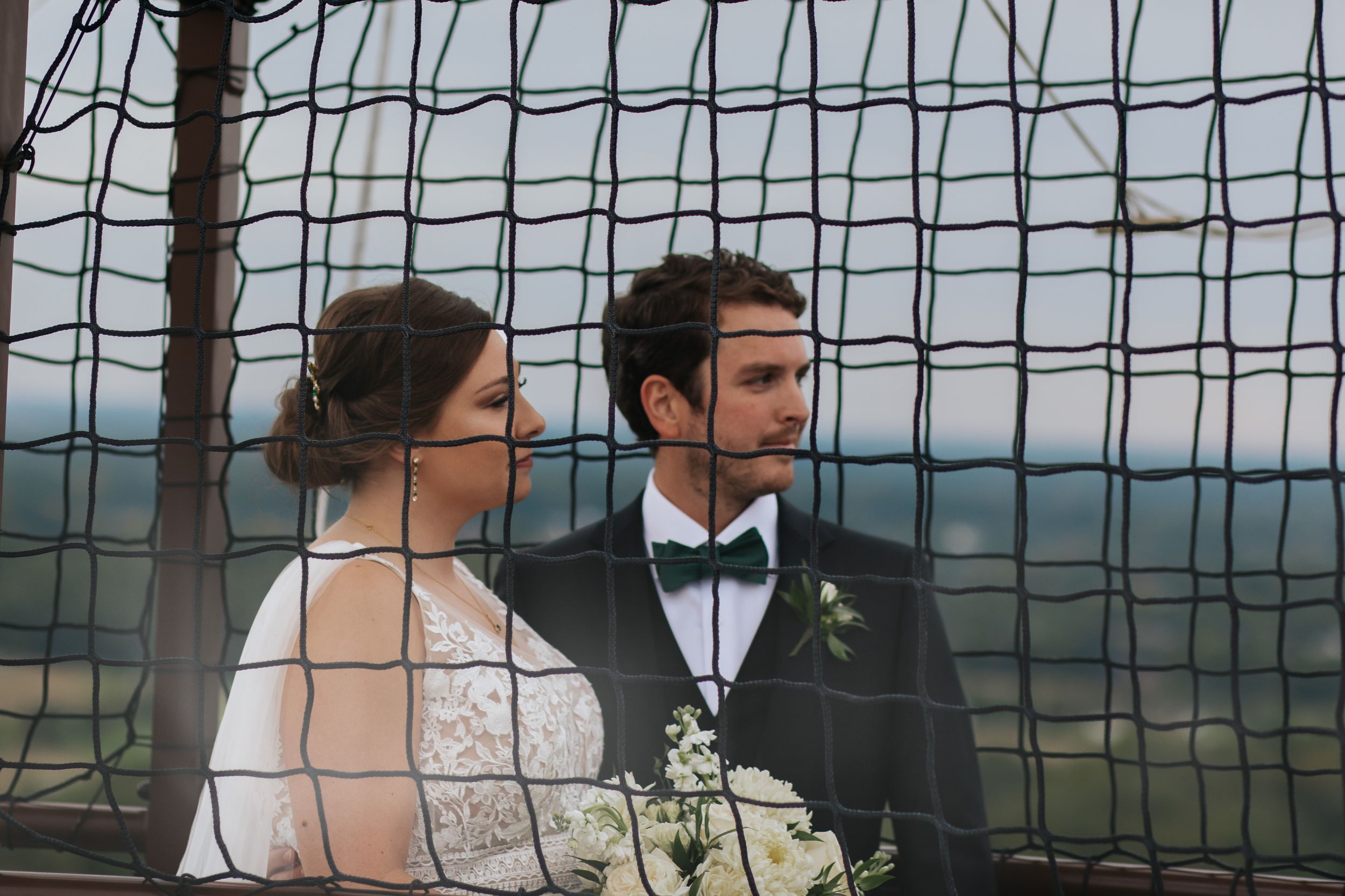 A wedding portrait framed by mesh netting with scenic mountain views in background.