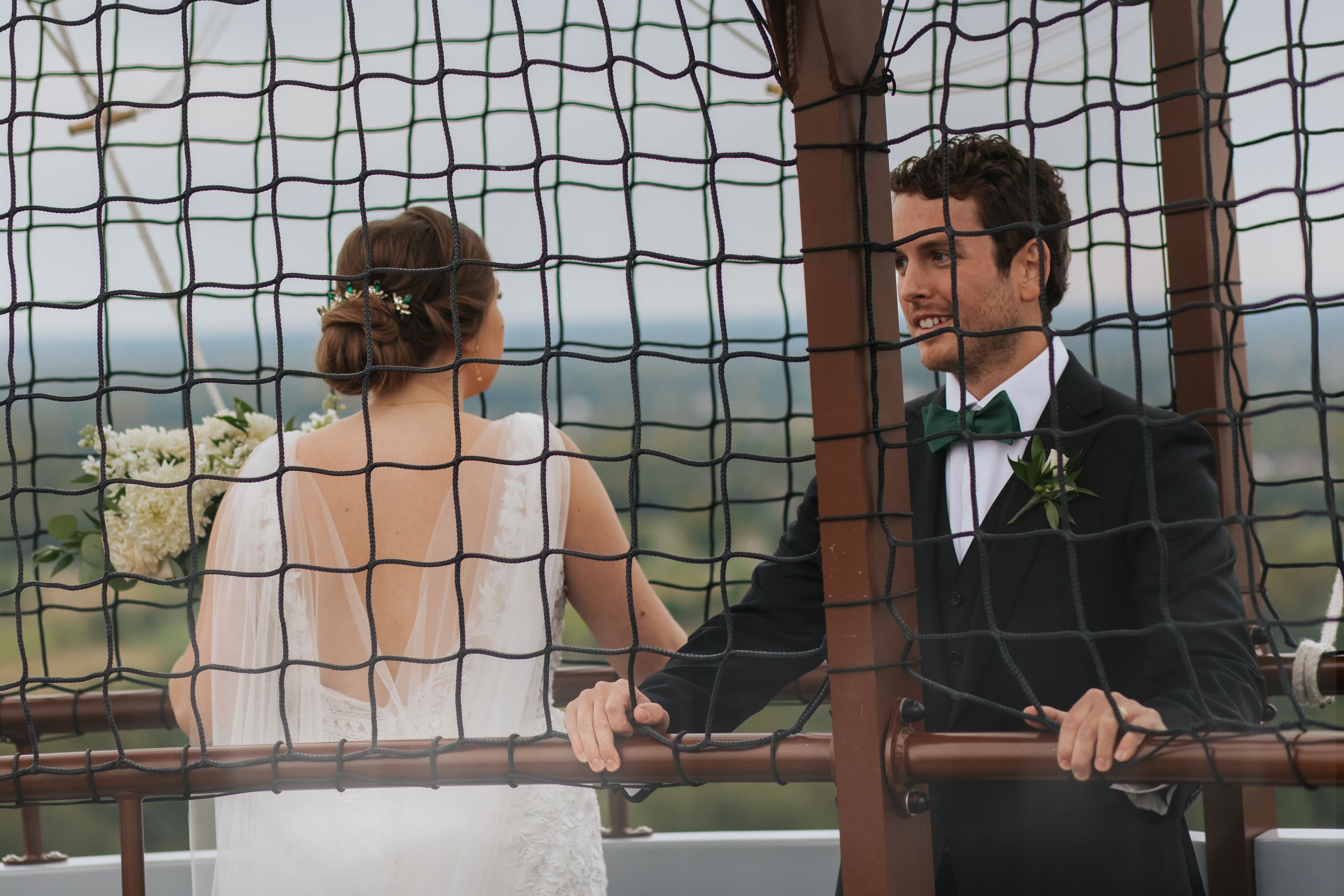 Wedding guests look through a decorative grid window at an outdoor venue.