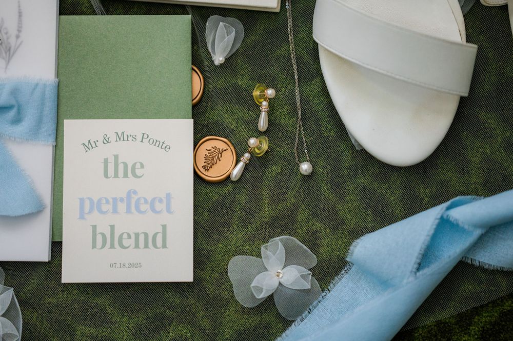 Wedding detail shot of 'The Perfect Blend' card with blue ribbon and floral accents.