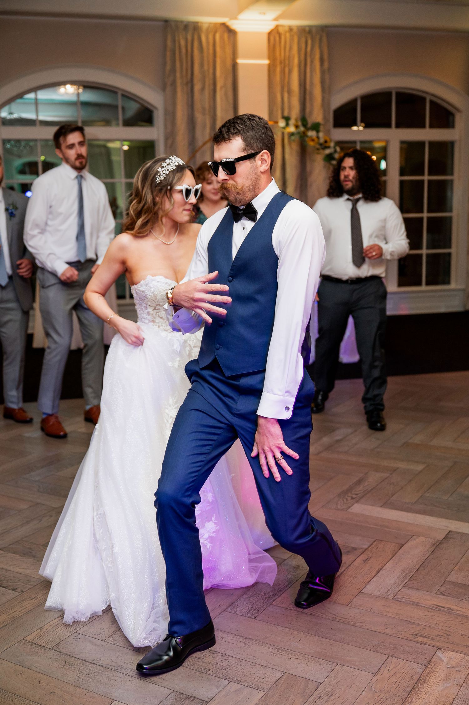 Couple dancing at a wedding reception with the bride in white dress and groom in navy suit.