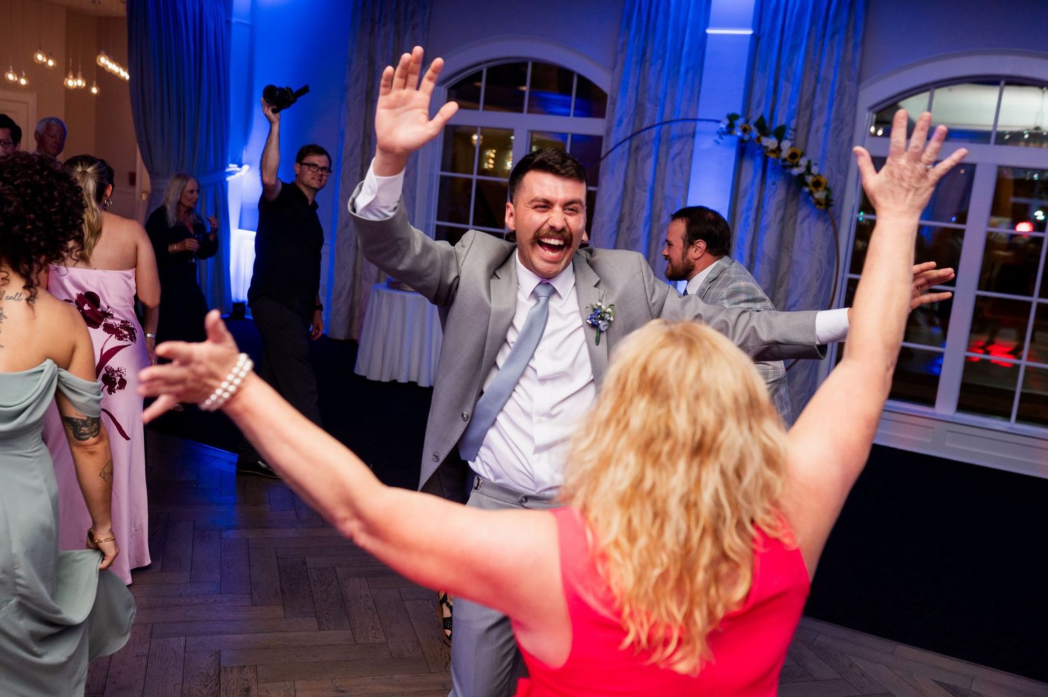 Wedding reception dance floor illuminated with blue lighting as guests celebrate.