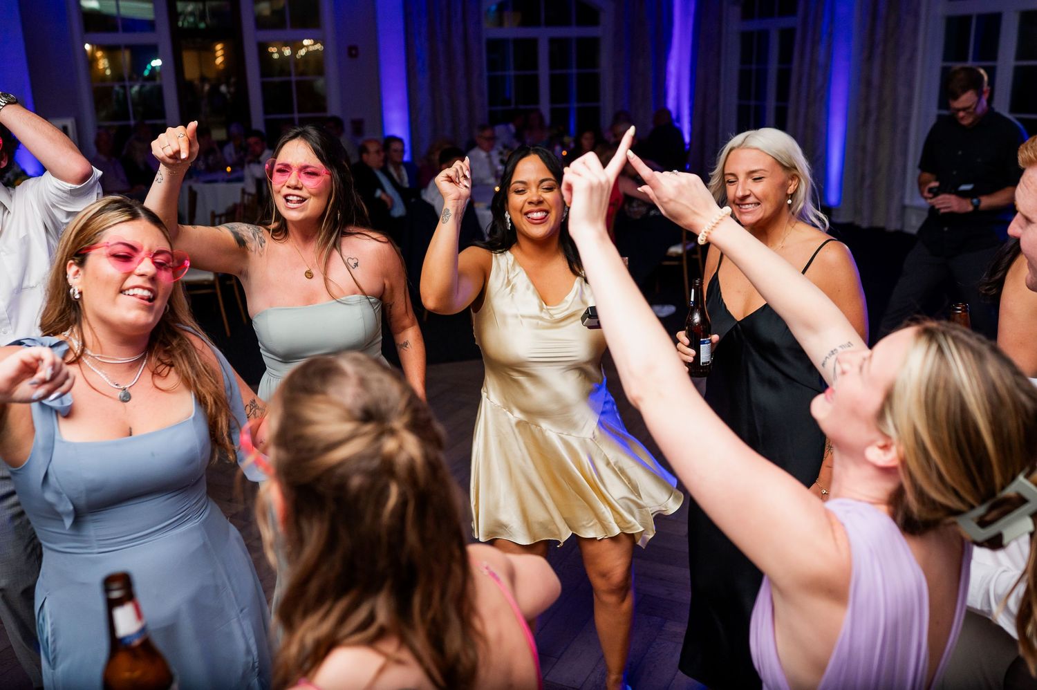 Lively dance floor filled with wedding guests celebrating under blue ambient lighting.
