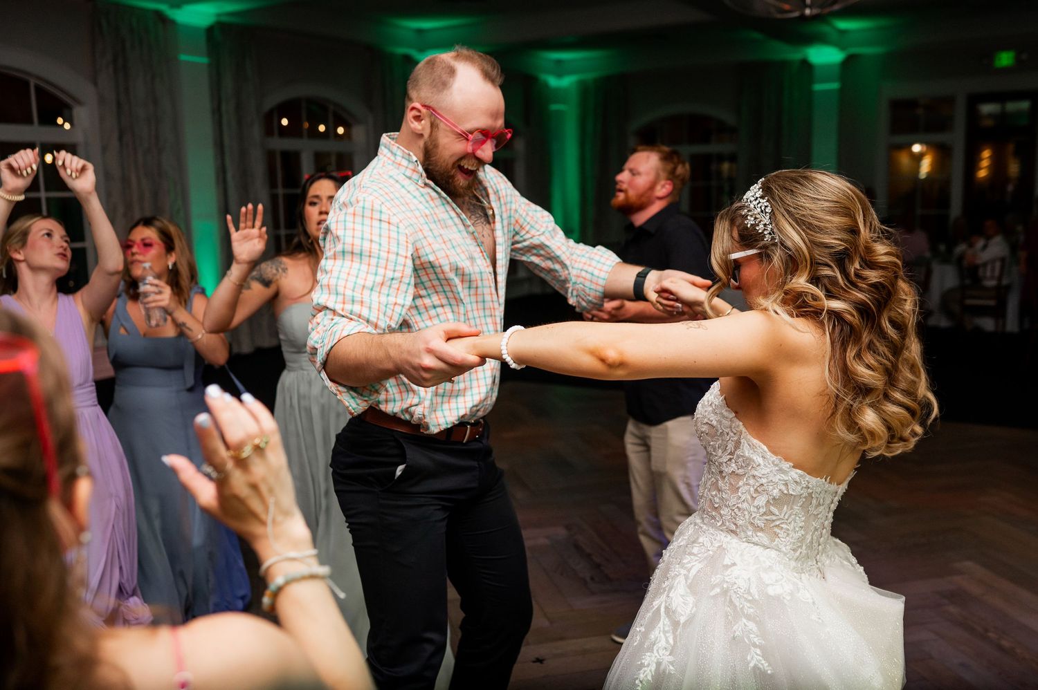 Wedding reception dance party with dramatic green lighting and guests dancing.