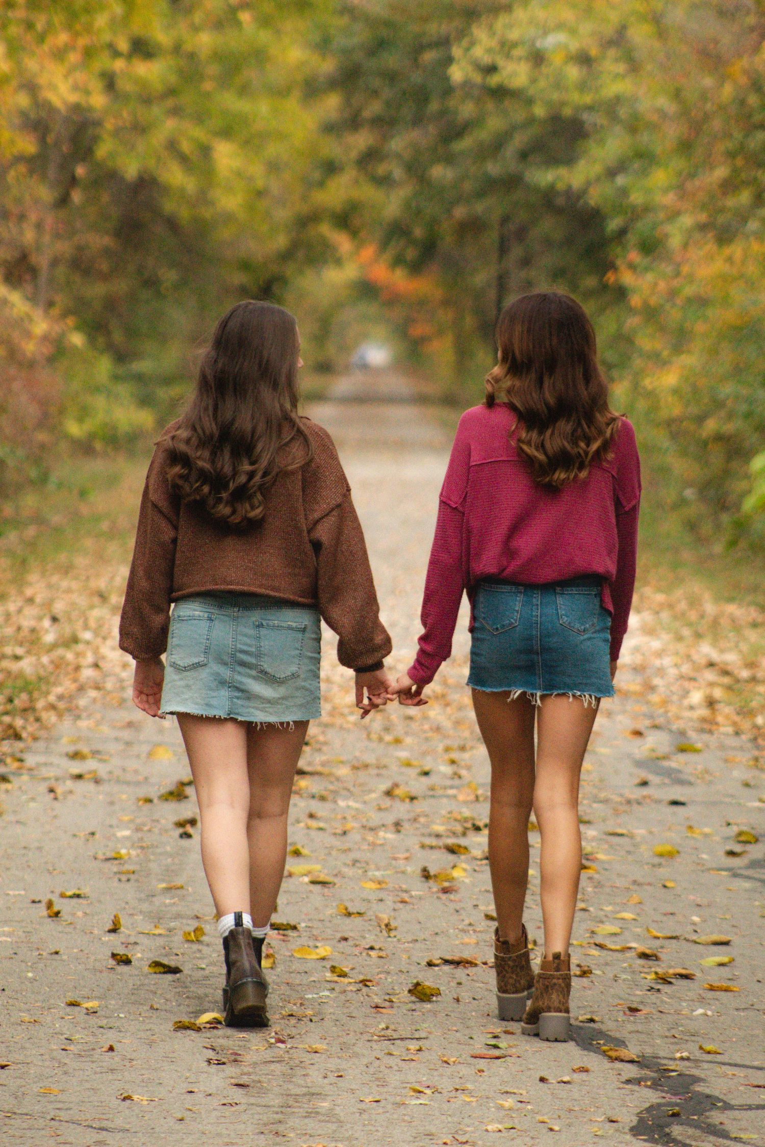 two friends walking down a lane filled with leaves