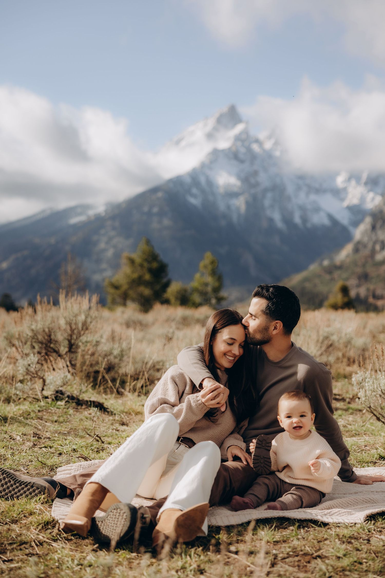 Family enjoying a picnic on a blanket with scenic mountain views in the background.