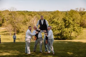 Wedding party members engage in fun group poses on a sunny hillside.