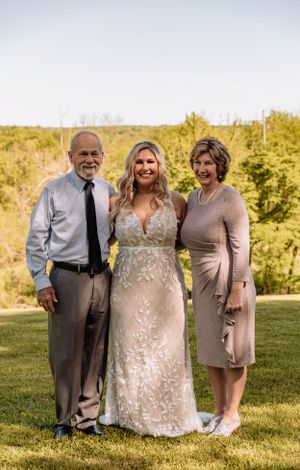 Wedding party members pose together on a sunny hillside in coordinated attire.