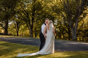 Scenic outdoor wedding photography with golden sunlight filtering through autumn trees.