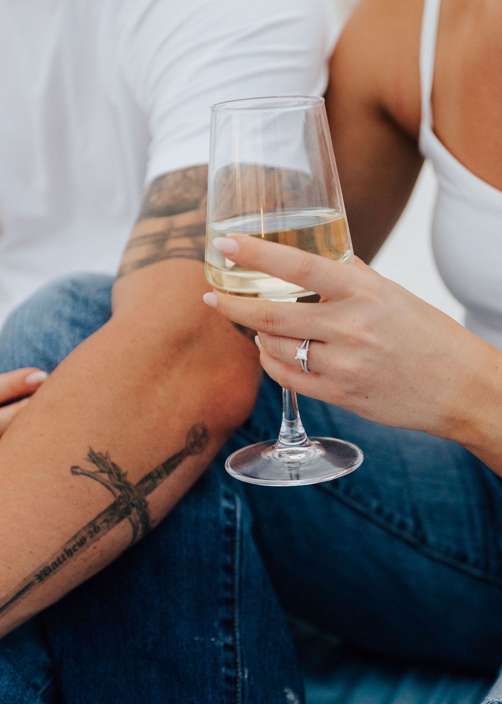 Close-up view of hands holding wine glass with engagement ring at engagement photoshoot in St. Pete Beach Tampa Florida