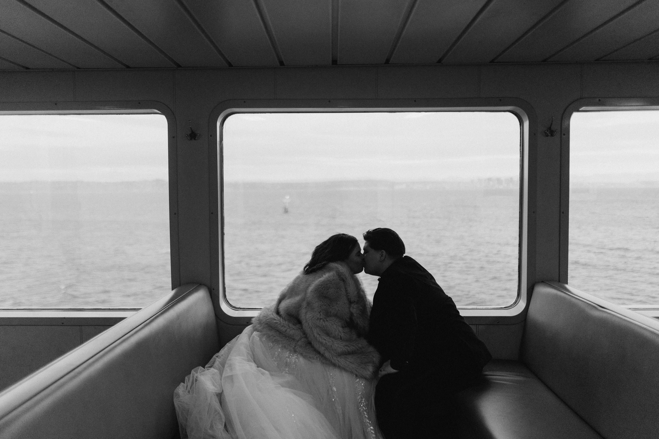 A black and white photograph shows silhouettes of passengers seated on a train looking out the window at the landscape.