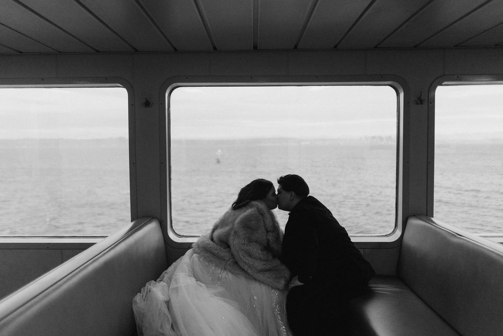 A black and white photograph shows silhouettes of passengers seated on a train looking out the window at the landscape.