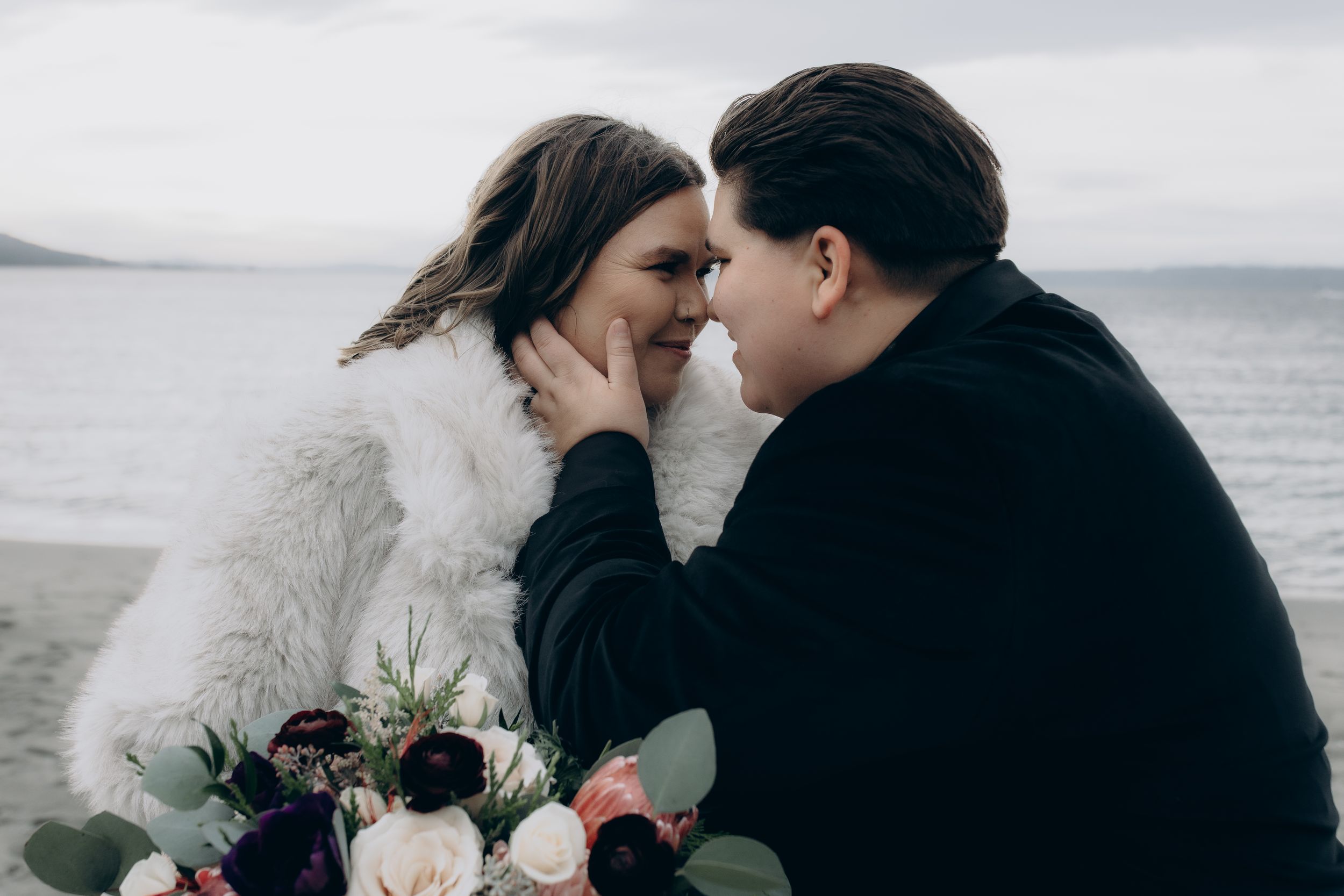 A couple embraces intimately against a misty coastal backdrop during their wedding photoshoot.