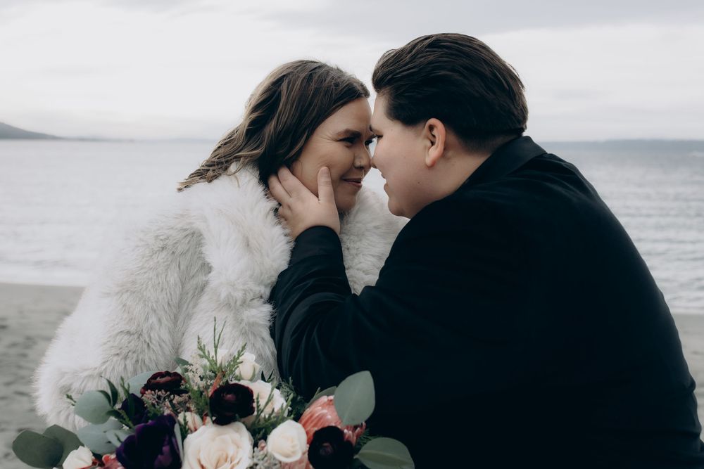 A couple embraces intimately against a misty coastal backdrop during their wedding photoshoot.