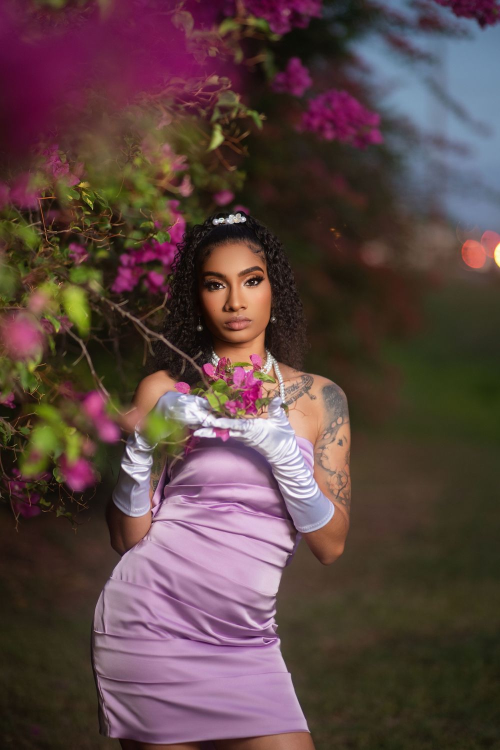Romantic portrait session with flowing lavender dress and white opera gloves amid purple blossoms.