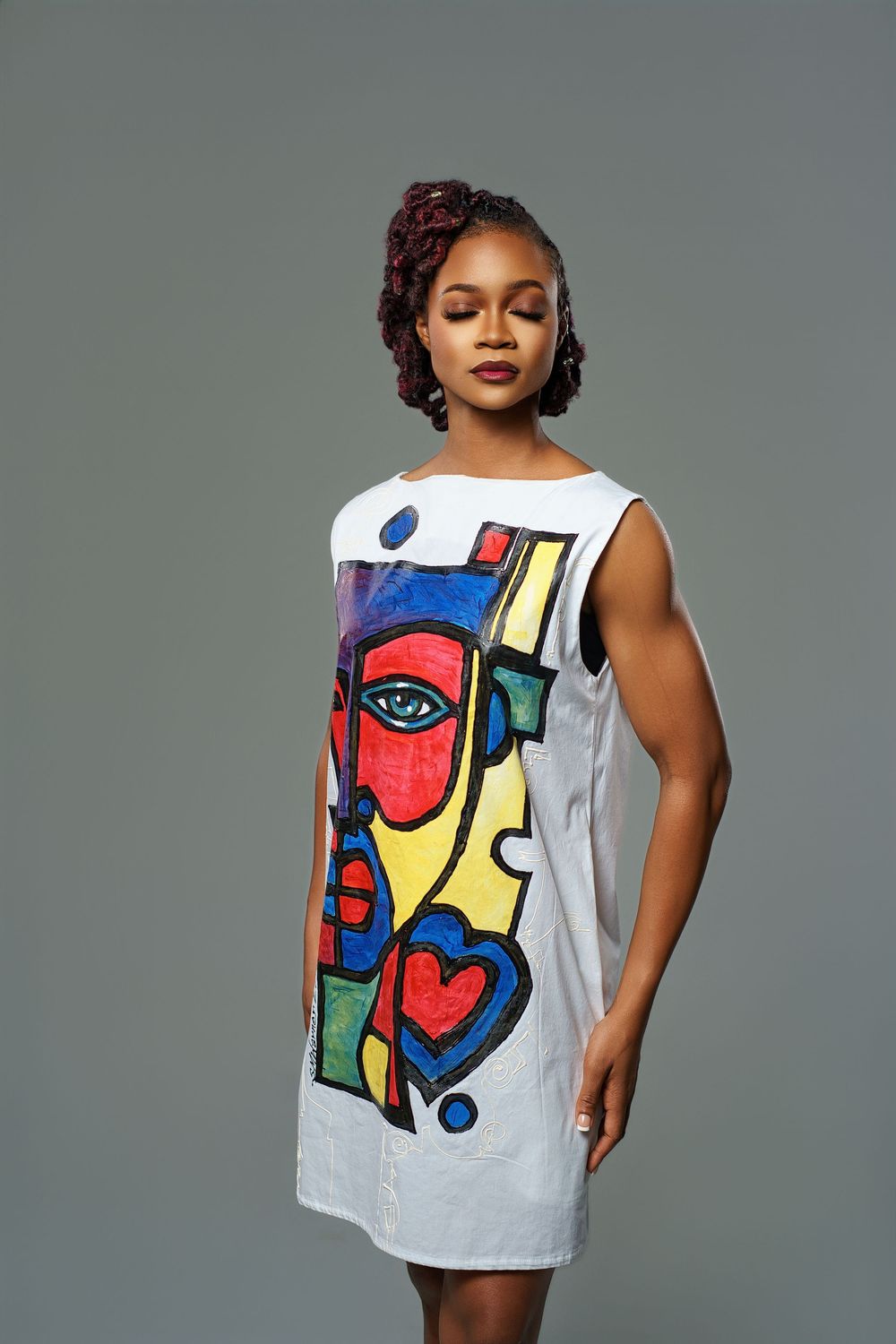 Artistic tank top featuring colorful abstract face design in primary colors on light gray background.