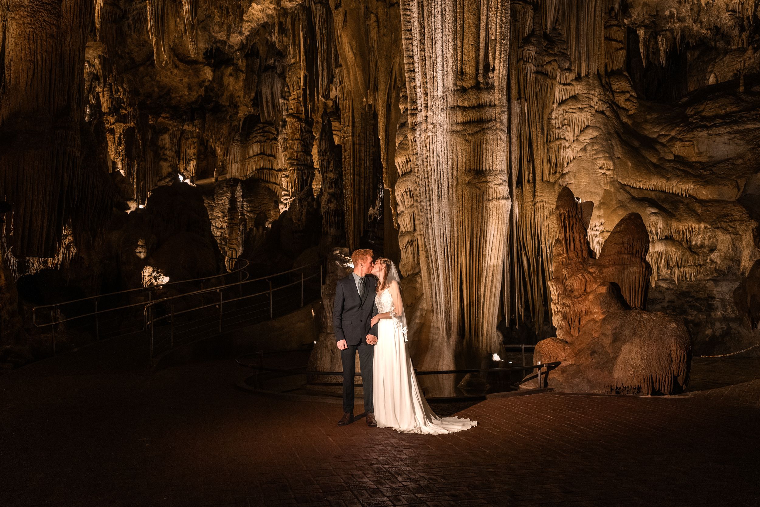 Illuminated cave formations and stalactites in a dark underground cavern with dramatic lighting and shadows.
