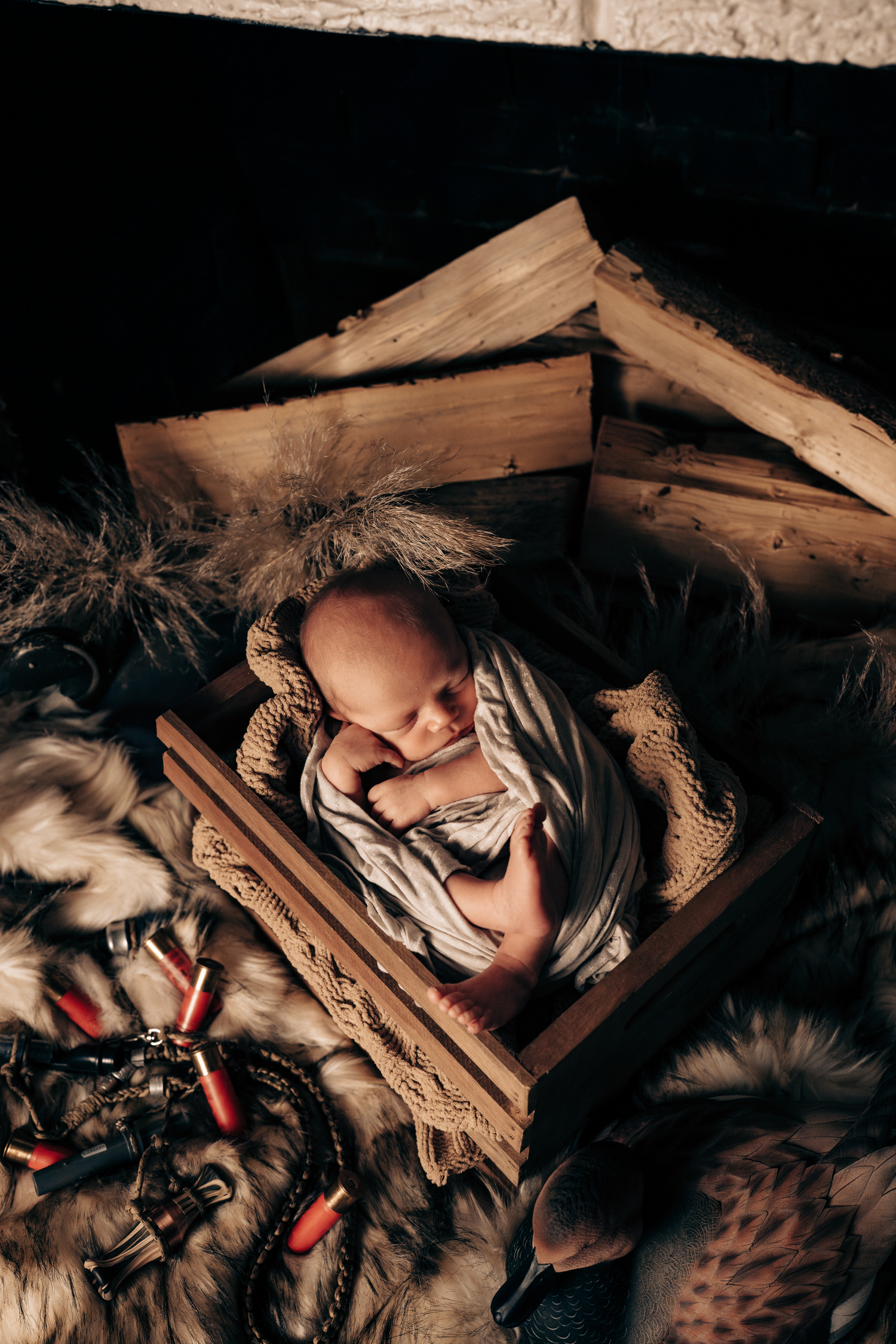 Newborn baby wearing Santa hat rests on cream colored fabric in natural light.