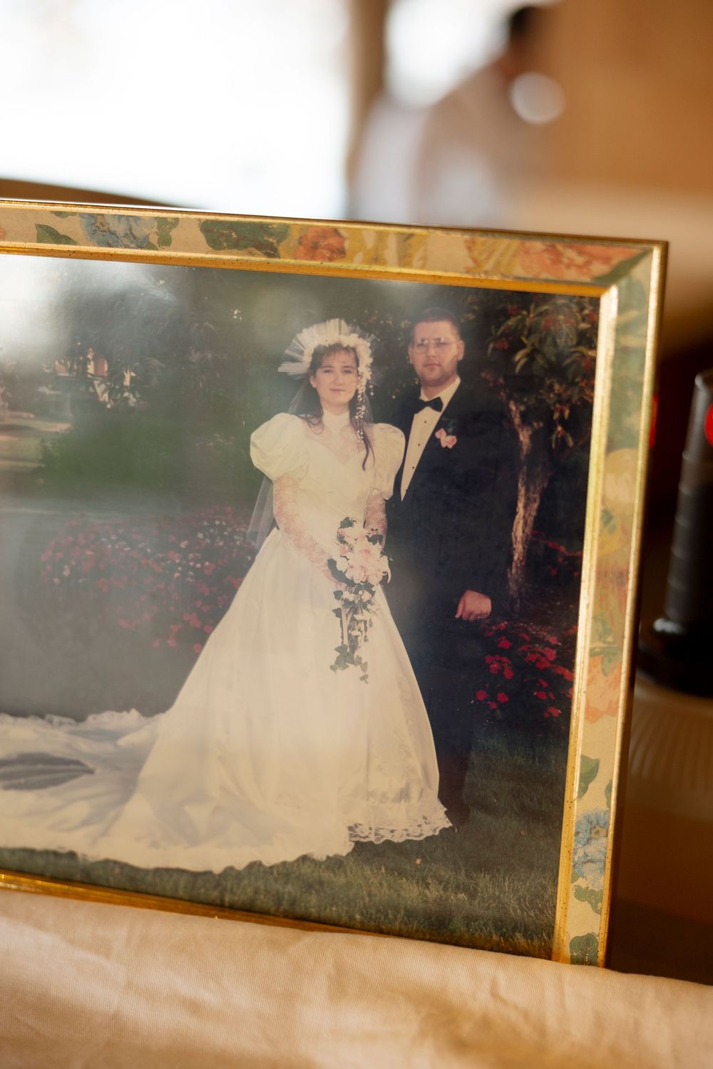 A vintage wedding photograph in a gold frame shows a couple in traditional formal attire from decades past.