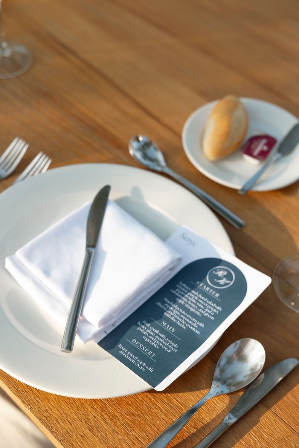White cloth napkins with blue menu cards arranged on wooden tables at a restaurant place setting.