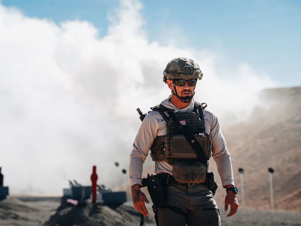 Tactical operators in protective gear moving across desert terrain during training.