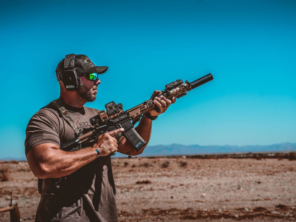 Shooters practicing rifle marksmanship on desert range under bright blue sky.