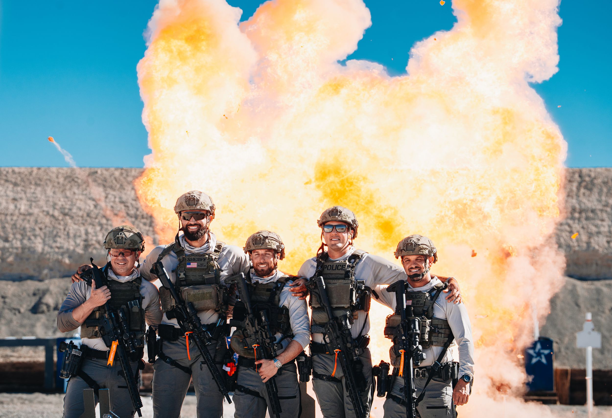 Team of operators standing in formation with fiery explosion behind them.